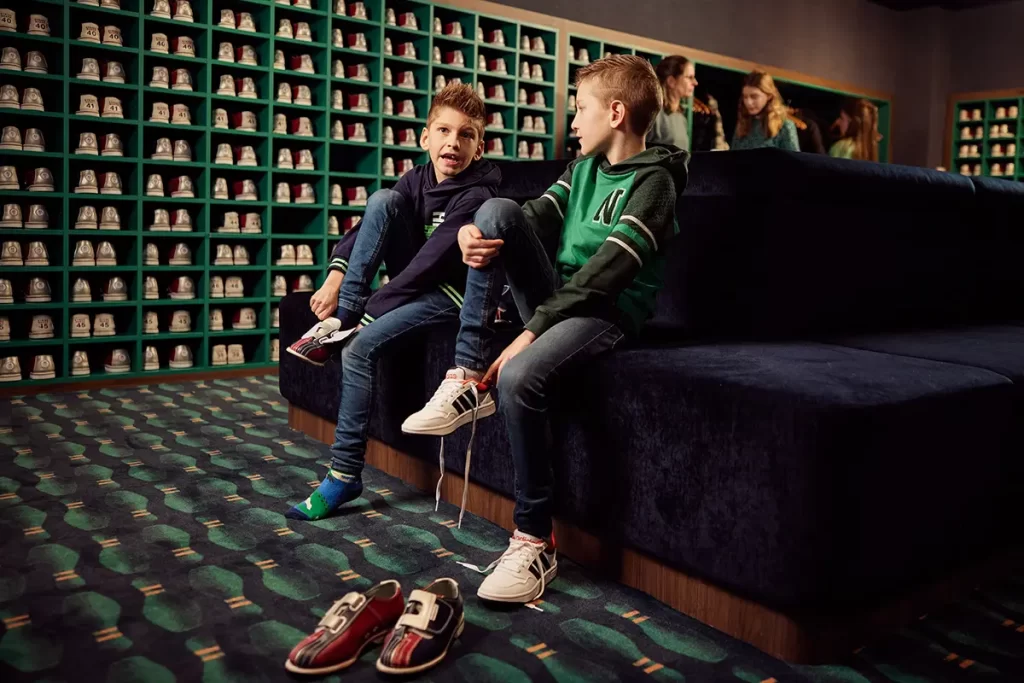 jongetjes die schoenen aantrekken in de bowlingbaan