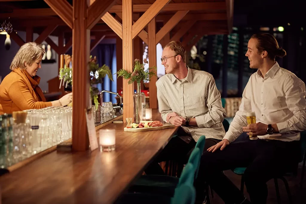 2 mensen die een drankje drinken aan de bar