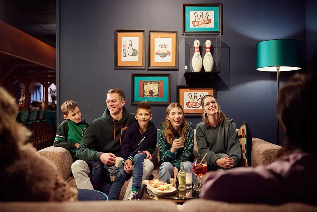 gezin geniet van drankje op de bank in bowlingbaan